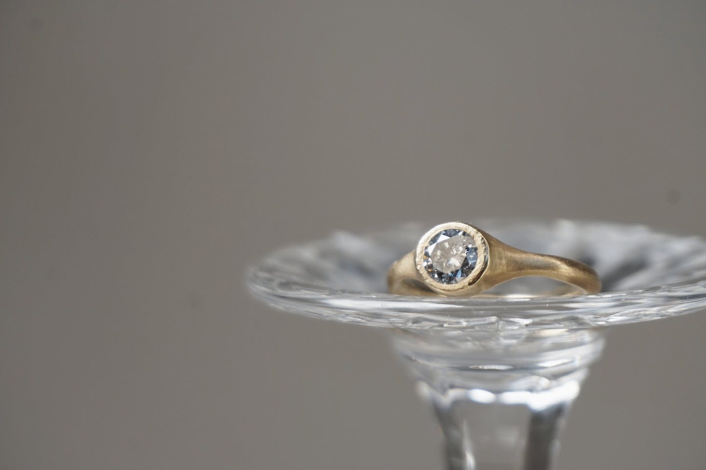 Close-up view of natural salt and pepper diamond set in yellow gold, highlighting the stone’s speckled inclusions and soft polished surface.